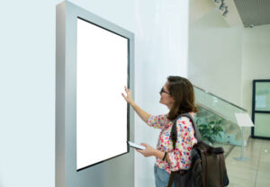 Woman with phone uses self-service desk with touch screen